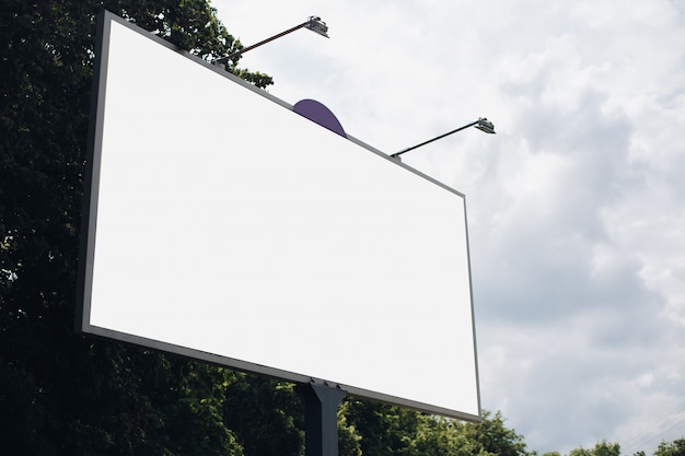 Bilbard con pubblicità multicolore e illuminazione si trova sulla strada alla luce del giorno, foto sotto