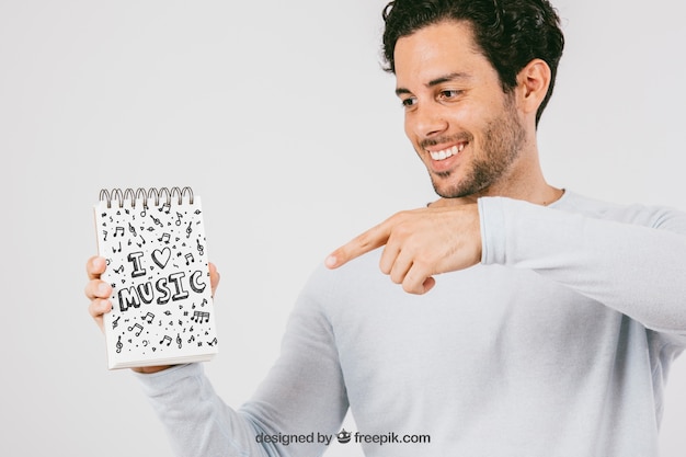 PSD gratuito diseño de mock up con hombre sonriente señalando la libreta