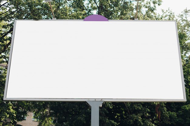 Een groot reclamebord met een reclamefoto erop in het park op straat