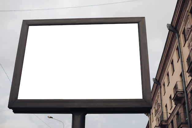 Een groot reclamebord met interessante informatie en reclame erop geïnstalleerd langs een brede straat in het stadscentrum