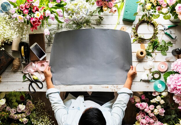 Floreria que muestra el papel vacío del espacio del diseño en la tabla de madera