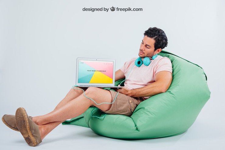 PSD gratuito giovane ragazzo seduto con gli auricolari e il computer portatile mock up