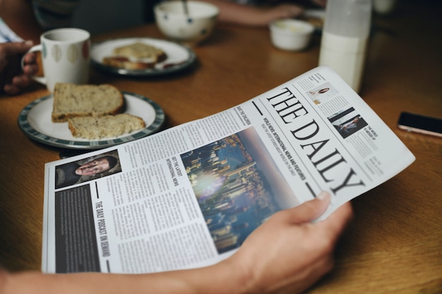 Hombre leyendo las noticias en la mesa del desayuno.