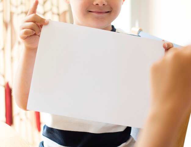 Kleine jongen met een blanco papier mockup