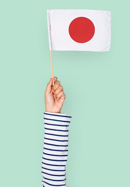 Mano sosteniendo la bandera japonesa