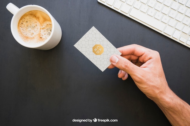 Gratis PSD mock up van hand bedrijf visitekaartje met koffie en toetsenbord