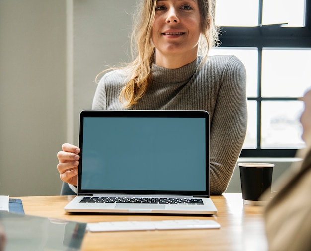 Mujer feliz con una pantalla en blanco de la computadora portátil
