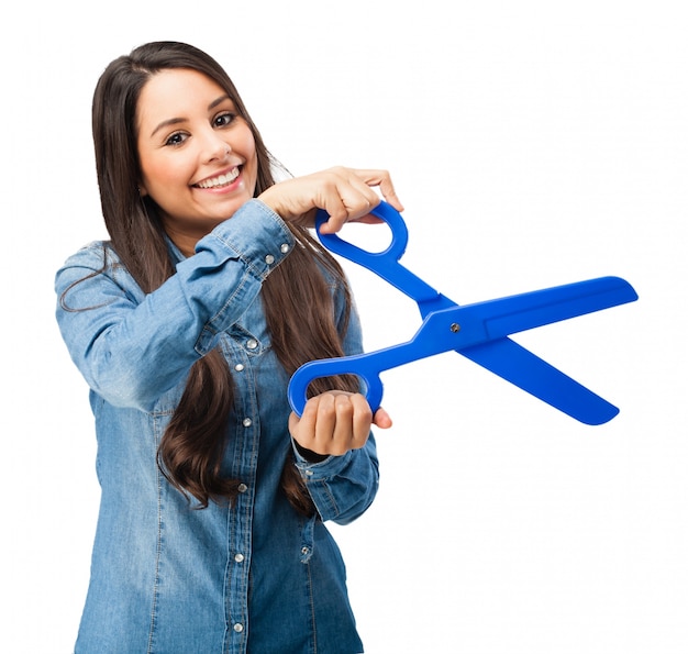 Mujer joven sujetando unas tijeras de plástico azules