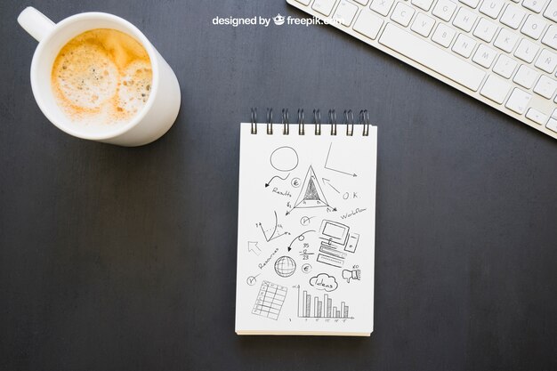 Notebook con disegni, tazza da caffè e tastiera