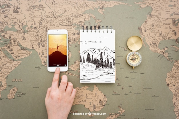 Smartphone, libreta y brújula sobre map del mundo