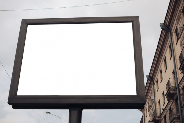 Un grande cartellone pubblicitario con informazioni e pubblicità interessanti installato lungo una larga strada nel centro della città