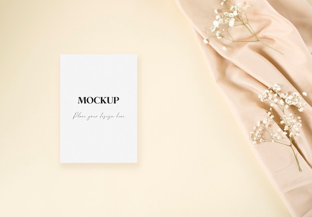 Carte d'invitation de mariage maquette avec gypsophile blanc et tissu nude sur fond beige