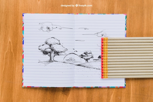 PSD gratuit dessin au crayon sur un cahier, des crayons et un fond en bois