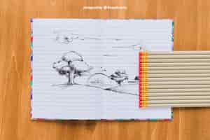 PSD gratuit dessin au crayon sur un cahier, des crayons et un fond en bois