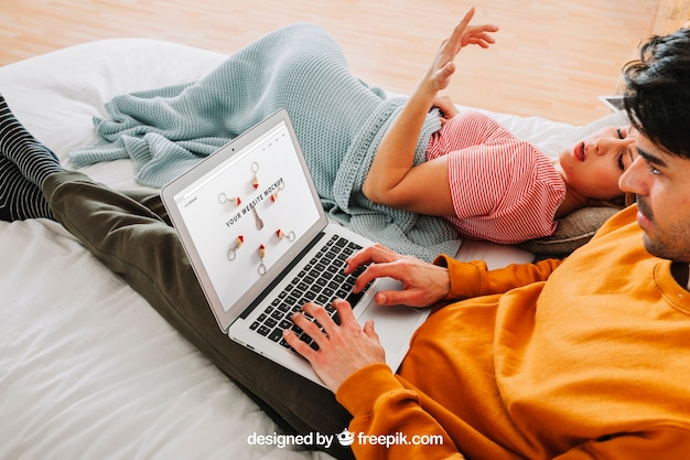 Casal moderno com laptop na cama