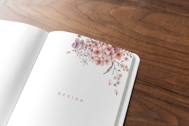 Maquete de caderno floral em uma mesa de madeira