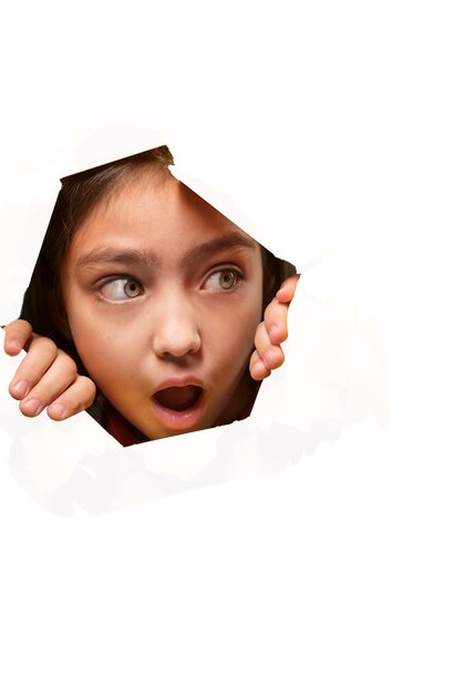 Retrato bonito da menina que olha através do papel cortado