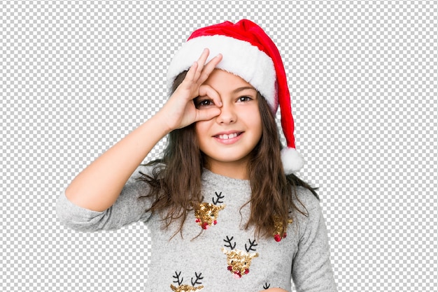 A menina que comemora o dia de natal excitou mantendo o gesto aprovado no olho.