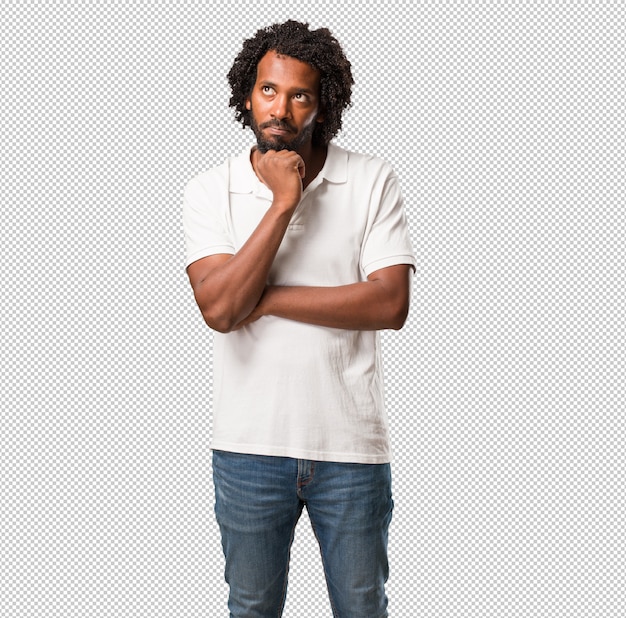 Afro-americano bonito duvidoso e confuso, pensando em uma idéia ou preocupado com algo