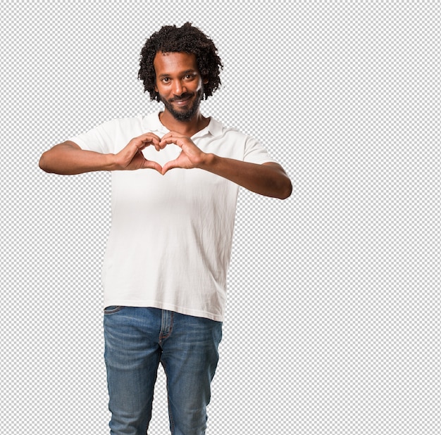 Afro-americano bonito fazendo um coração com as mãos, expressando o conceito de amor e amizade, feliz e sorridente