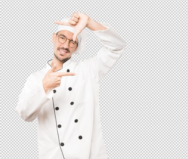 Amable joven chef haciendo un gesto de tomar una foto con las manos