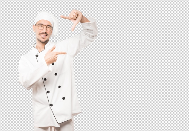 Amable joven chef haciendo un gesto de tomar una foto con las manos