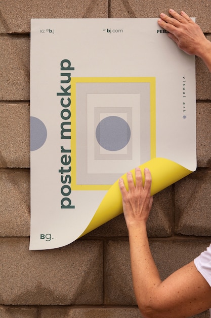 Ansicht einer Person, die eine Außenplakatattrappe an die Wand klebt