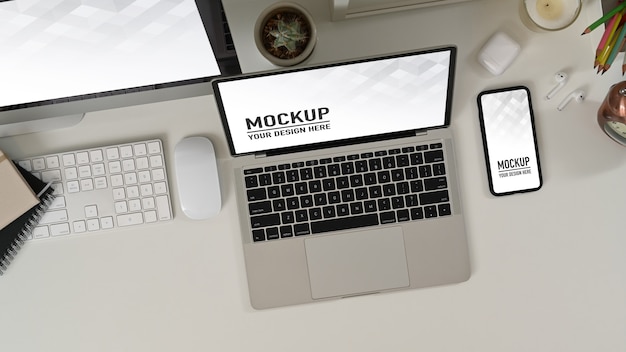 Arbeitsbereich mit Laptop, Smartphone und Desktop-Computer mit leerem Bildschirm