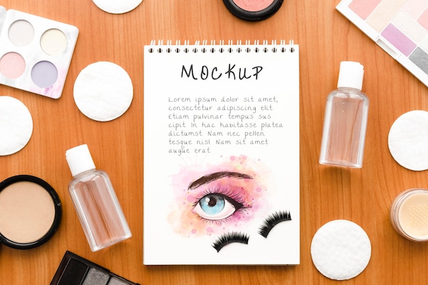 Arreglo de cosméticos de maquillaje de vista superior con maqueta de bloc de notas