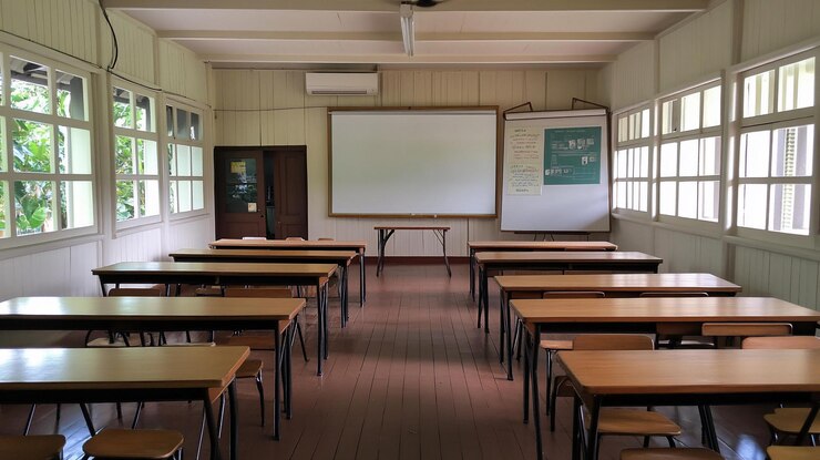 PSD aula vuota con scrivania in legno, lavagna e grandi finestre