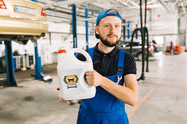 Automechaniker, der plastikdosenmodell halten kann