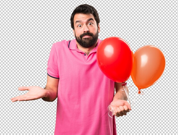 Beau jeune homme fait un geste sans importance et tenant des ballons