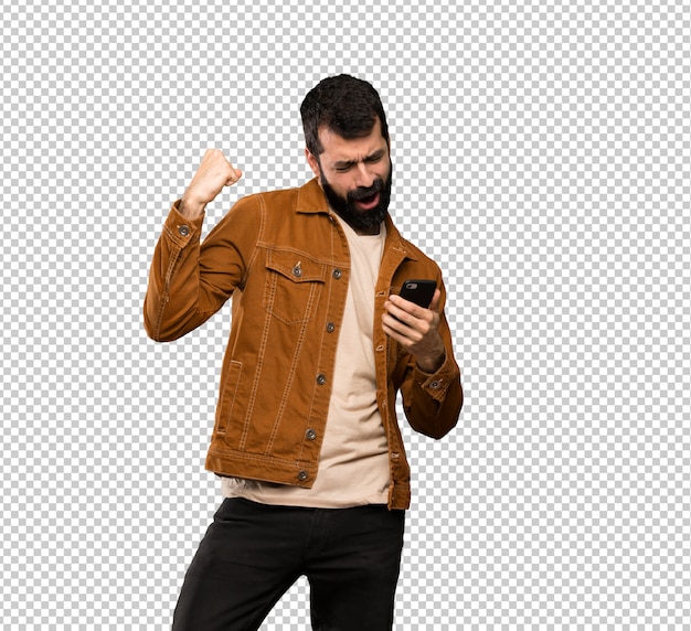 Bel homme à la barbe avec téléphone en position de victoire