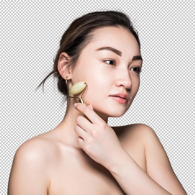 Bella joven asiática usando un rodillo facial de jade en su piel impecable Bella cara de primer plano Conceptual de tratamientos faciales con piedras semipreciosas aisladas en gris con espacio de copia