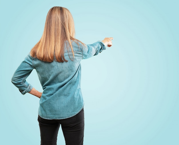 PSD belle femme âgée vue arrière, main sur la hanche, pointant avec l'autre main à un objet dans la distance