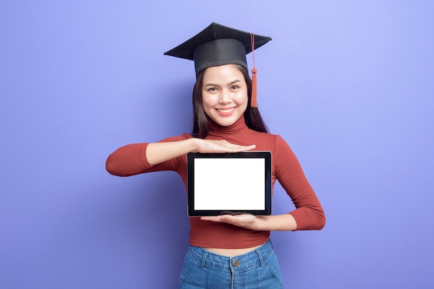 Belle femme en chapeau de graduation tient une maquette de tablette