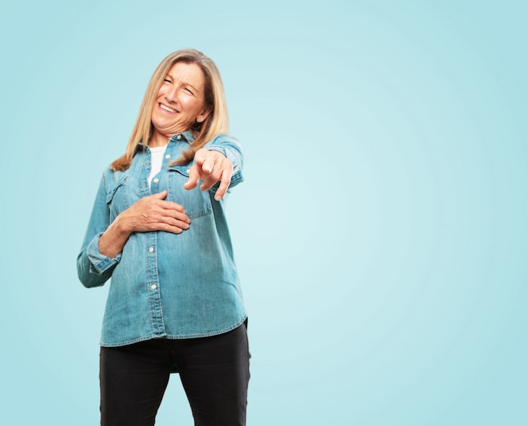 PSD belle femme senior riant de quelque chose d'hilarant et pointant vers vous