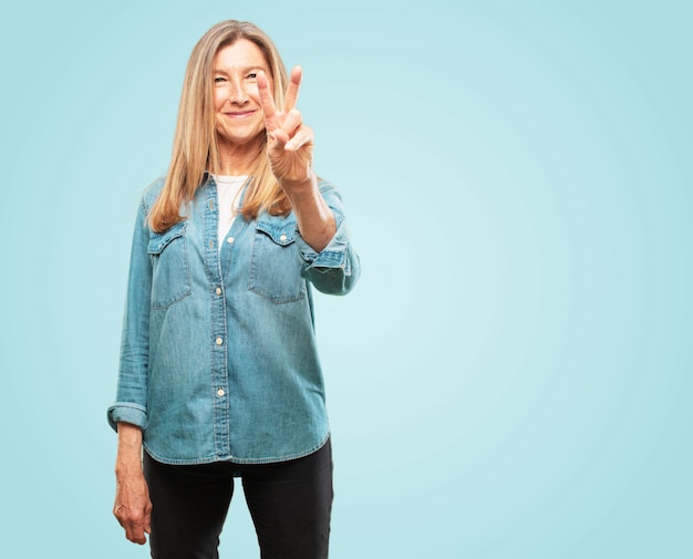 Belle femme senior souriant et regardant satisfait et heureux, comptant le numéro deux avec les doigts