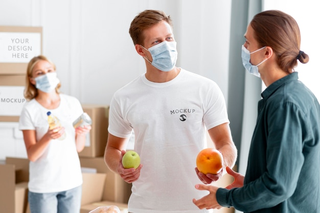 PSD des bénévoles avec des masques médicaux distribuant de la nourriture à l'homme