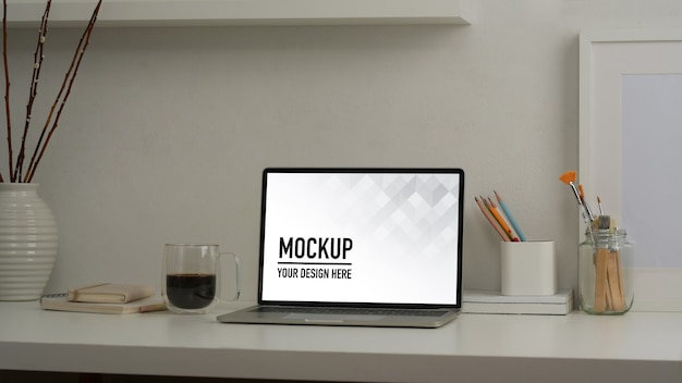 Beschnittener Schuss des Scheinlaptops auf weißem Tisch mit Büromaterial