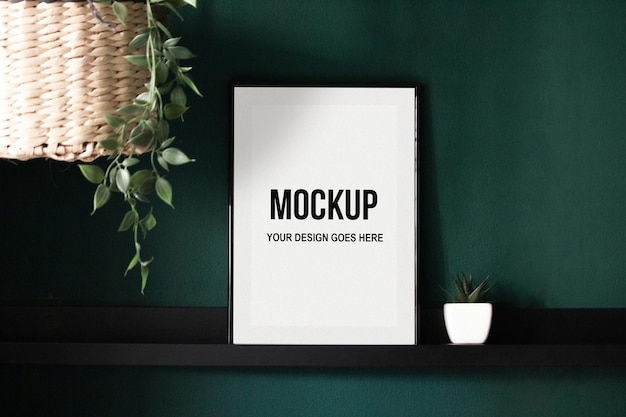 Black picture frame on shelf with green wall and plants
