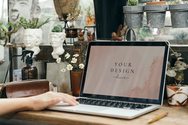 Blumenhändler mit einem Laptop-Mockup in einem Gewächshaus