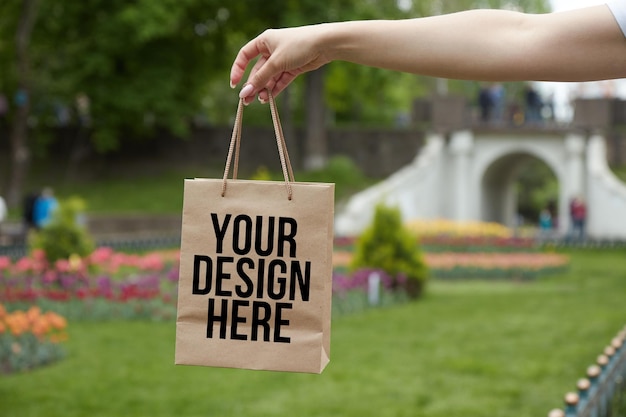 Bolsa de papel de maqueta con asas chica sosteniendo en la mano primer plano color cambiable su diseño