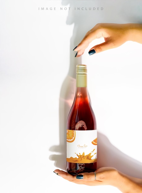 Una botella de vino rosado en manos femeninas con una maqueta de un logotipo.