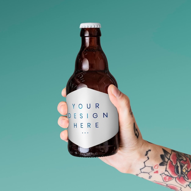 Brazo tatuado sosteniendo una maqueta de botella de vidrio marrón