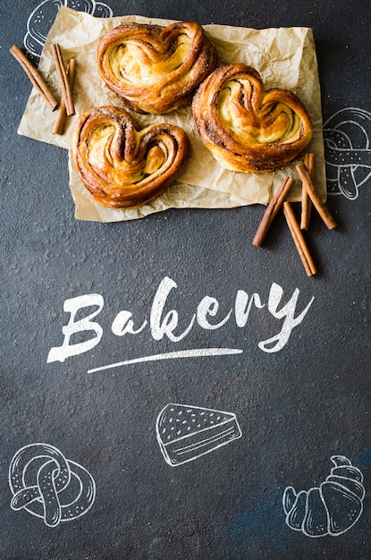 Brioches à la cannelle fraîche et parfumée. Pâtisseries traditionnelles faites maison sur fond sombre.