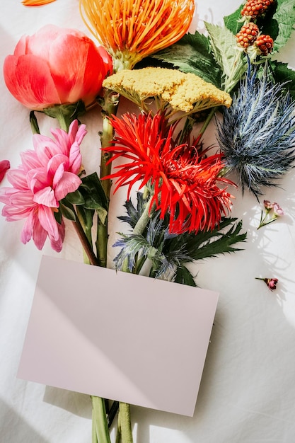 Buquê de flores coloridas em um lençol branco com uma maquete de cartão