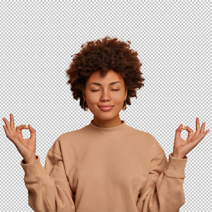 PSD calm relieved dark skinned woman takes deep breath keeps hands sideways in zen gessture reaches nirvana and practices yoga stands with closed eyes stands stress free against brown wall