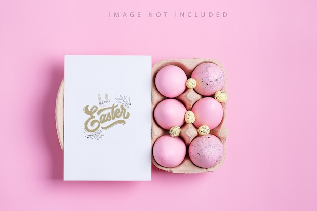 Cartão postal de maquete com ovos pintados de rosa e cartão de papel. conceito de feliz páscoa. vista do topo.