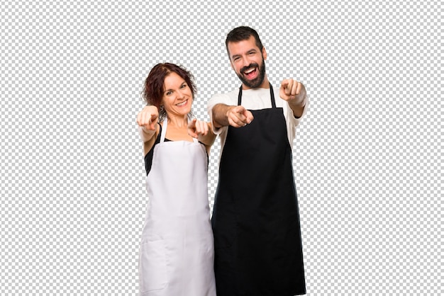 Casal de cozinheiros aponta o dedo para você enquanto sorrindo